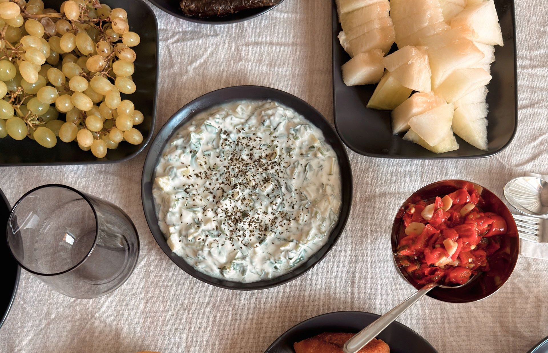 Tisch mit Vorspeisen von oben: Joghurt-Dip, gefüllte Weinblätter, Kibbeh und Obst