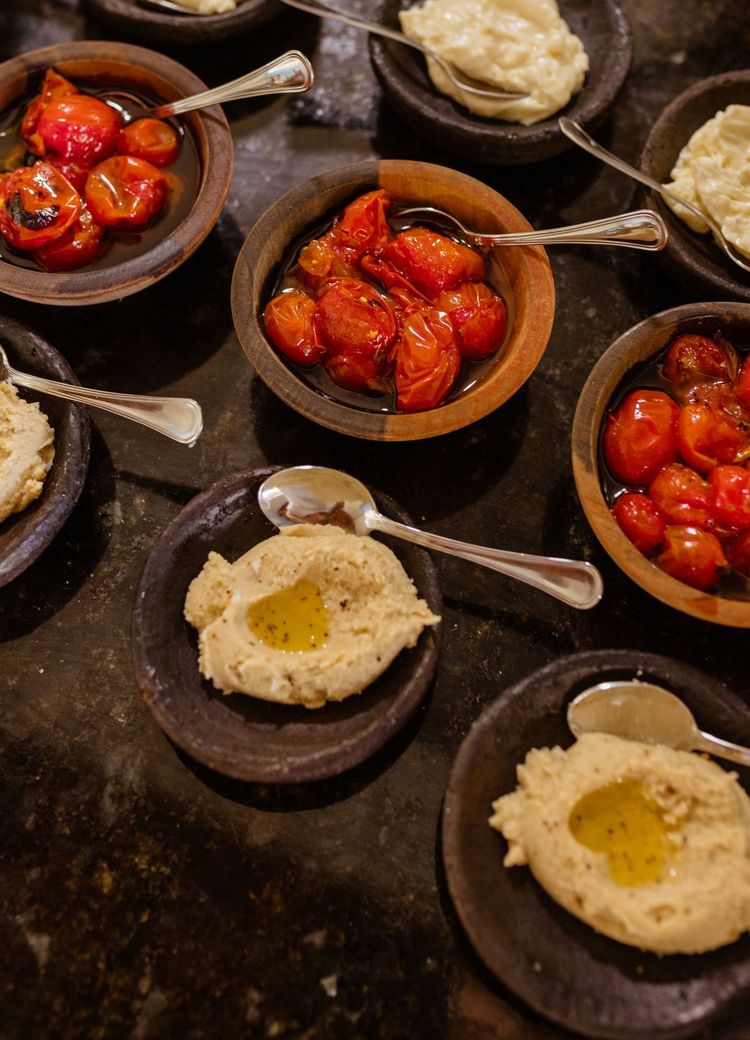 Tonschalen mit Hummus, Käsecreme und geschmorten Tomaten im warmen Licht